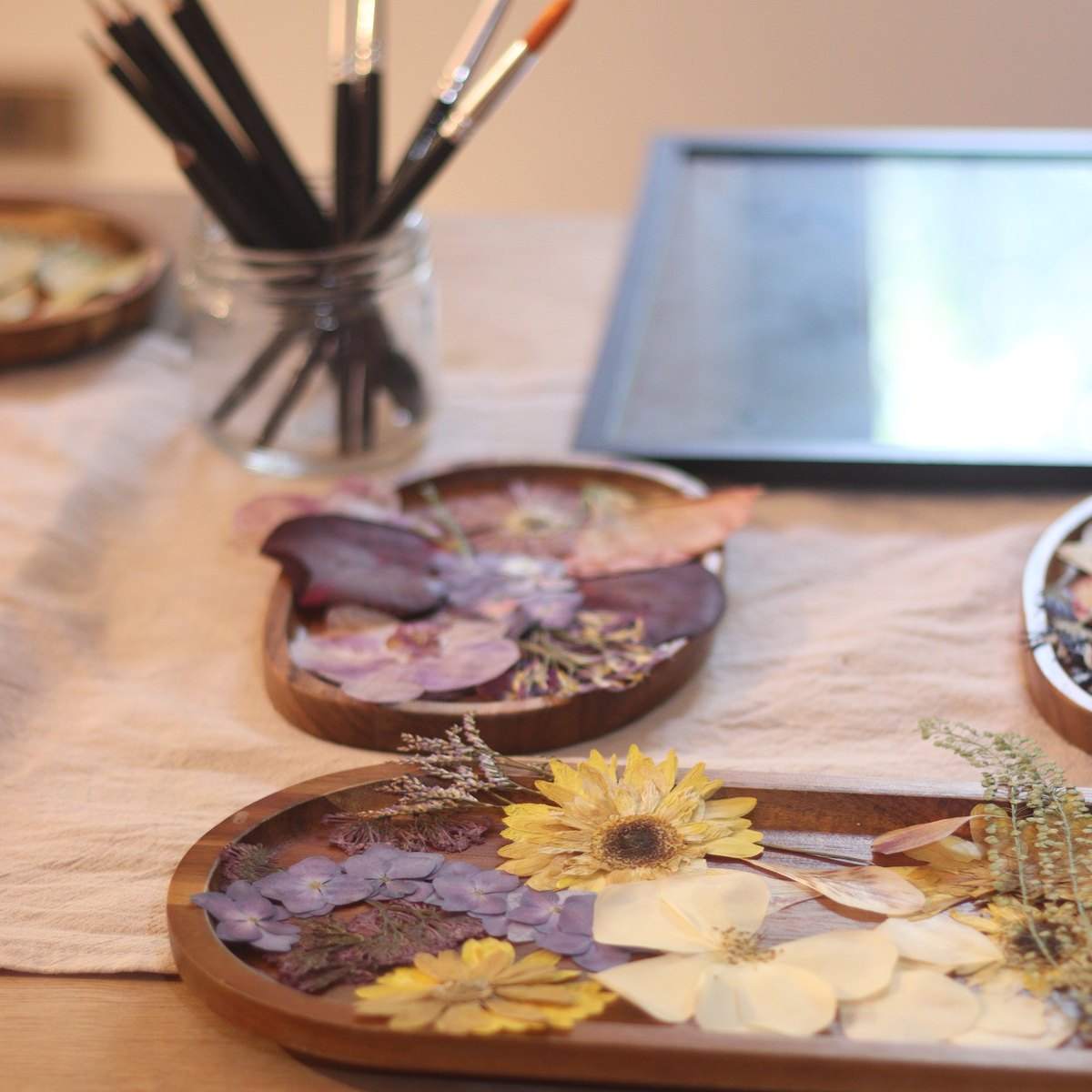 Bandejas de madera con flores prensadas y pinceles sobre la mesa del taller