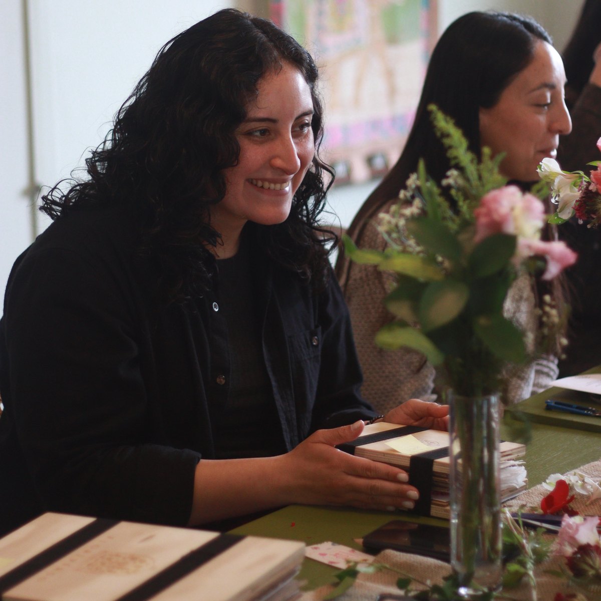 Participante sonriendo con su prensa Floriverso durante el taller de prensado floral